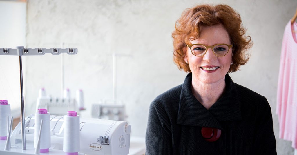 Woman with short red hair and glasses smiling at the camera