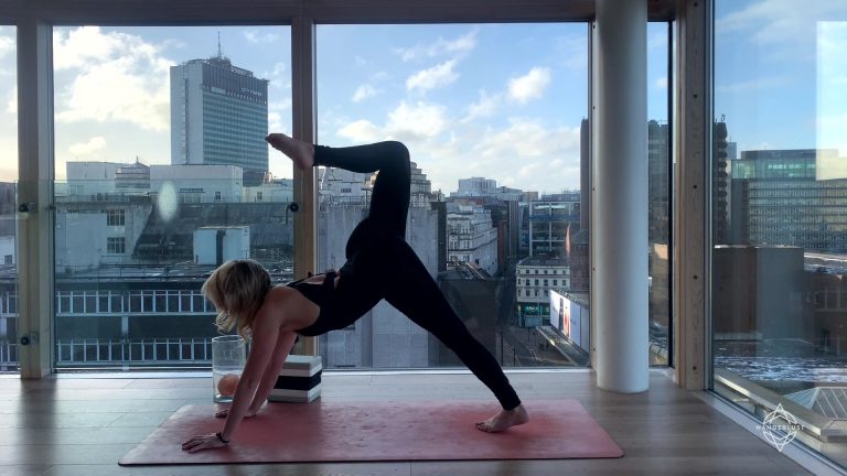 Woman doing yoga in front of large windows
