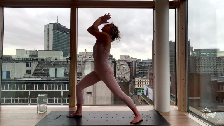 Person doing yoga in front of large windows