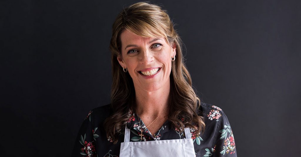 Woman in an apron smiling at the camera