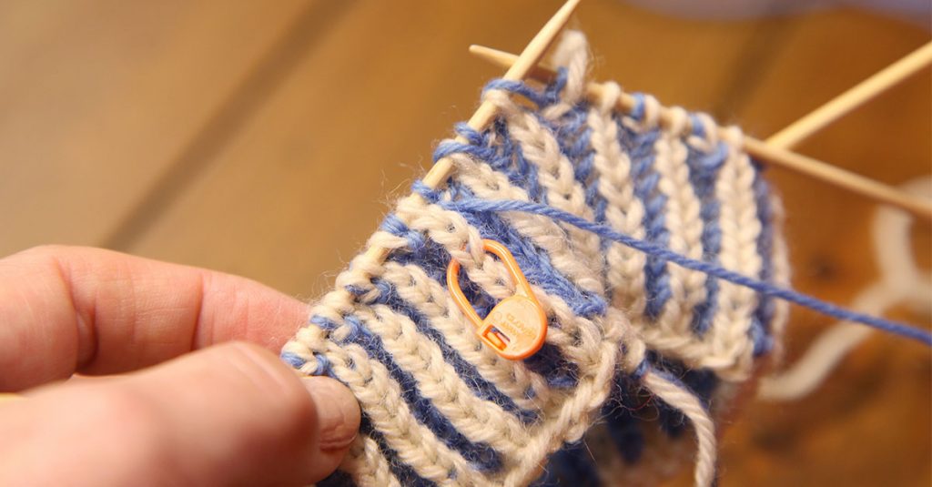 Stitch marker on blue and white knitting