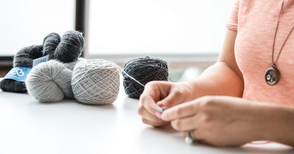 Woman knitting with colors of grey yarn
