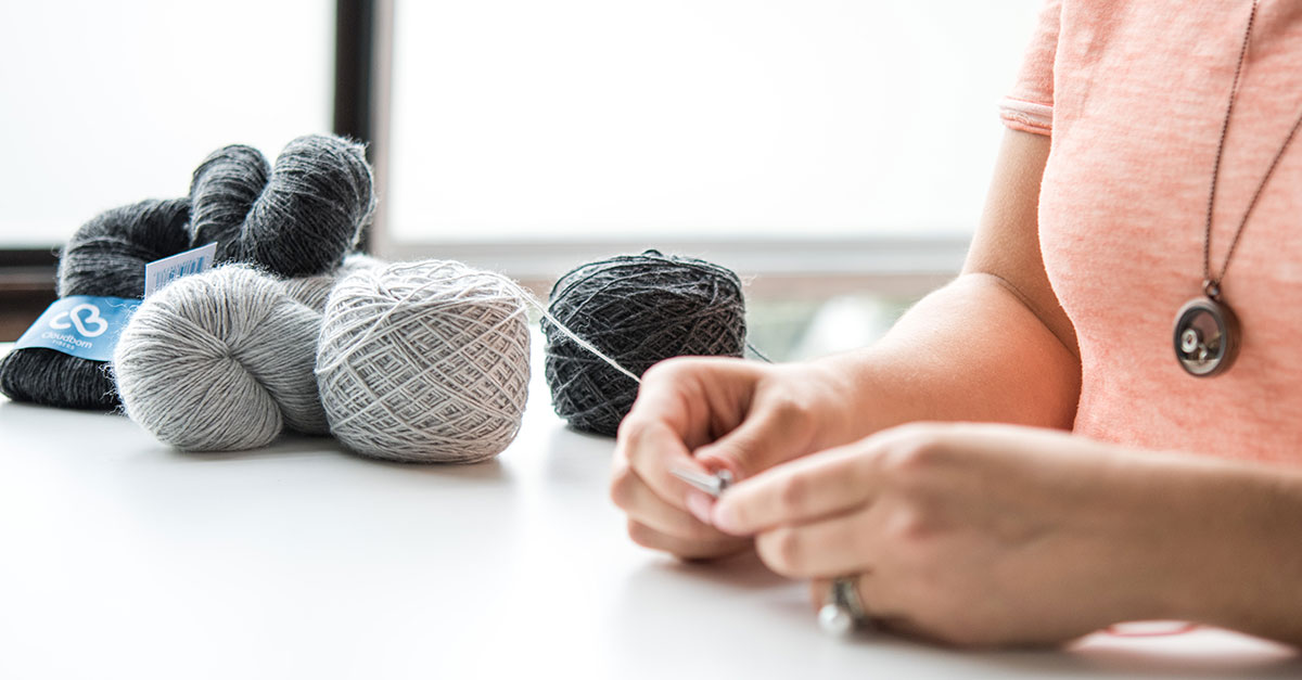 Woman knitting with colors of grey yarn