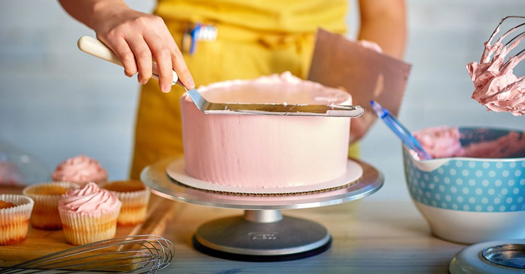 Smoothing a frosted pink cake