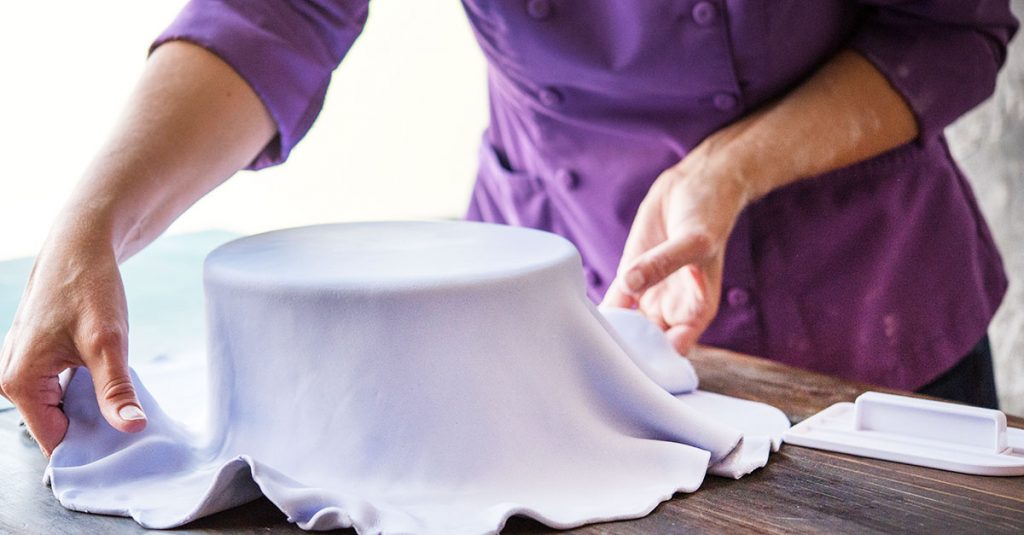 Covering a cake in lavender fondant