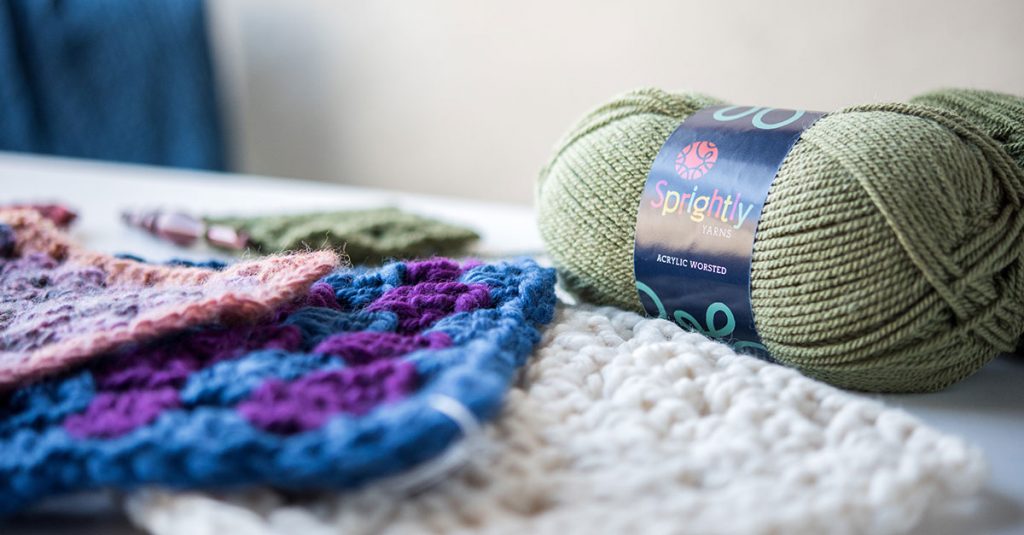 Knit squares and a green roll of yarn