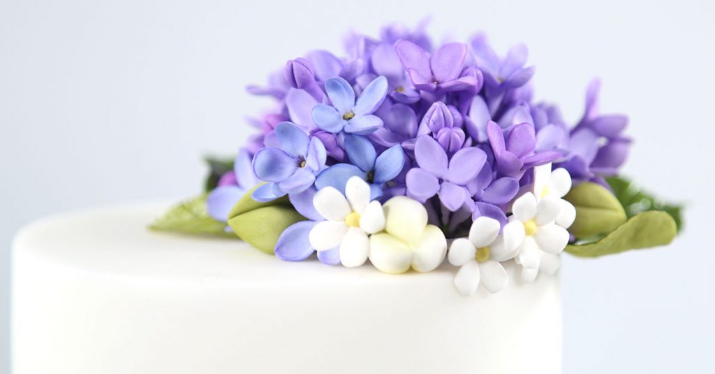 Purple and white sugar flowers on a cake