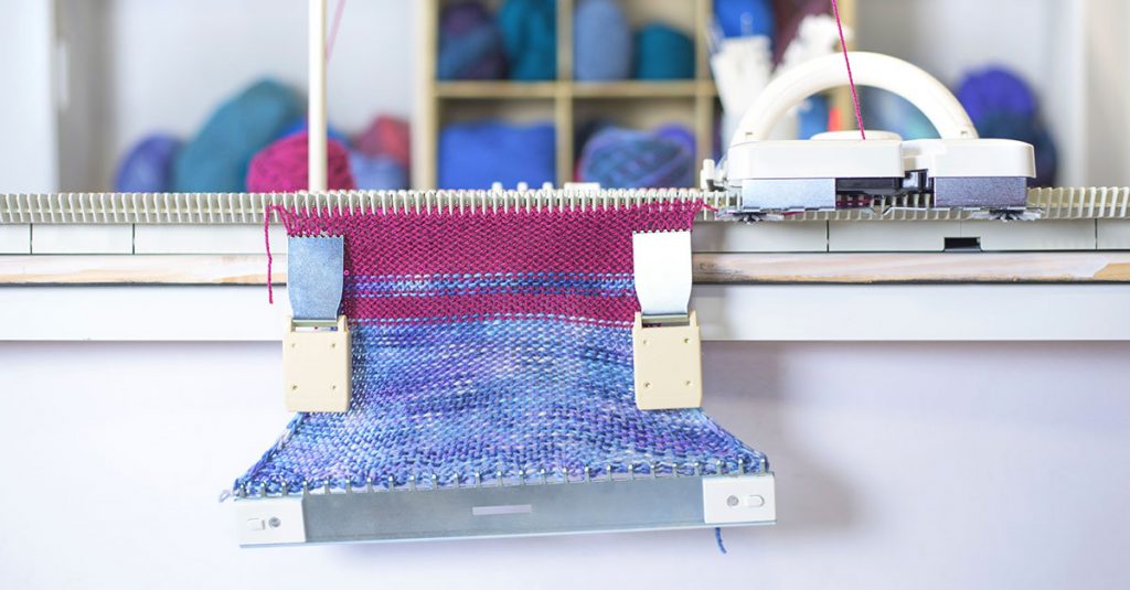 Machine knitting with blue and pink yarn