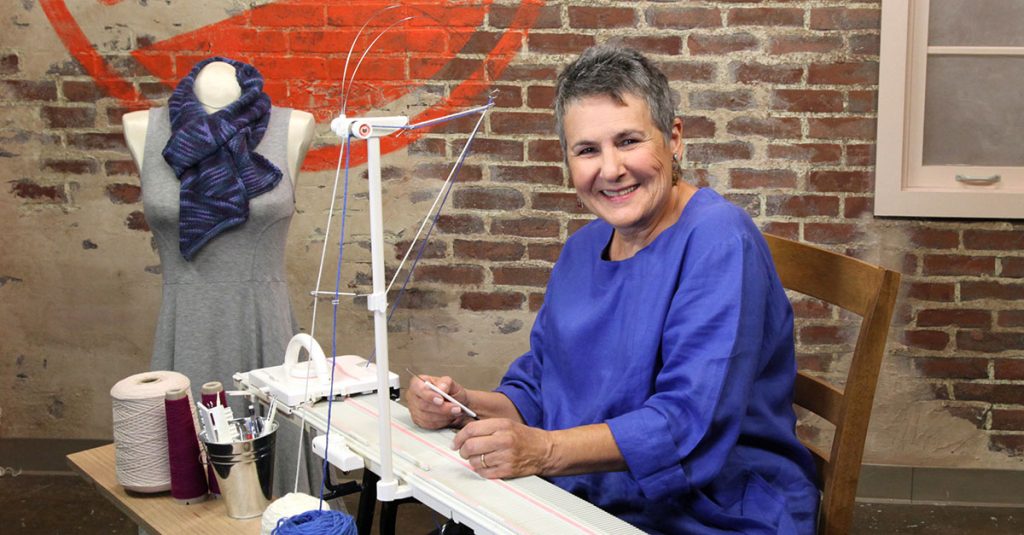 Woman smiling near a knitting machine