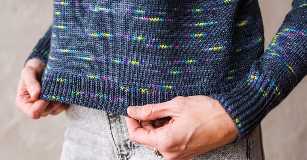 Person holding the hem of a knit sweater