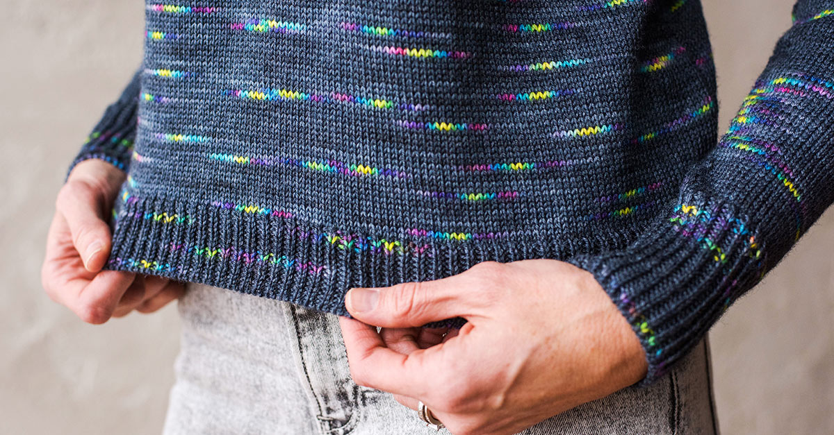 Person holding the hem of a knit sweater