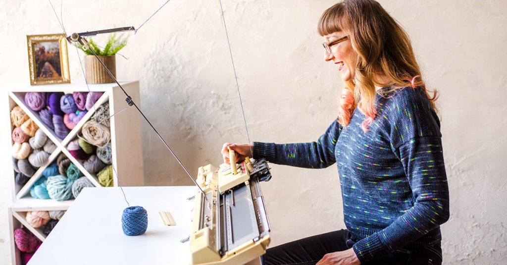 Woman in glasses machine knitting