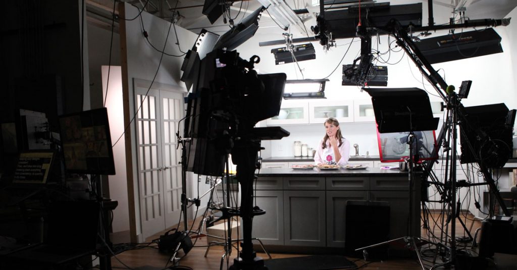 Behind the scenes of cameras at a woman in a kitchen