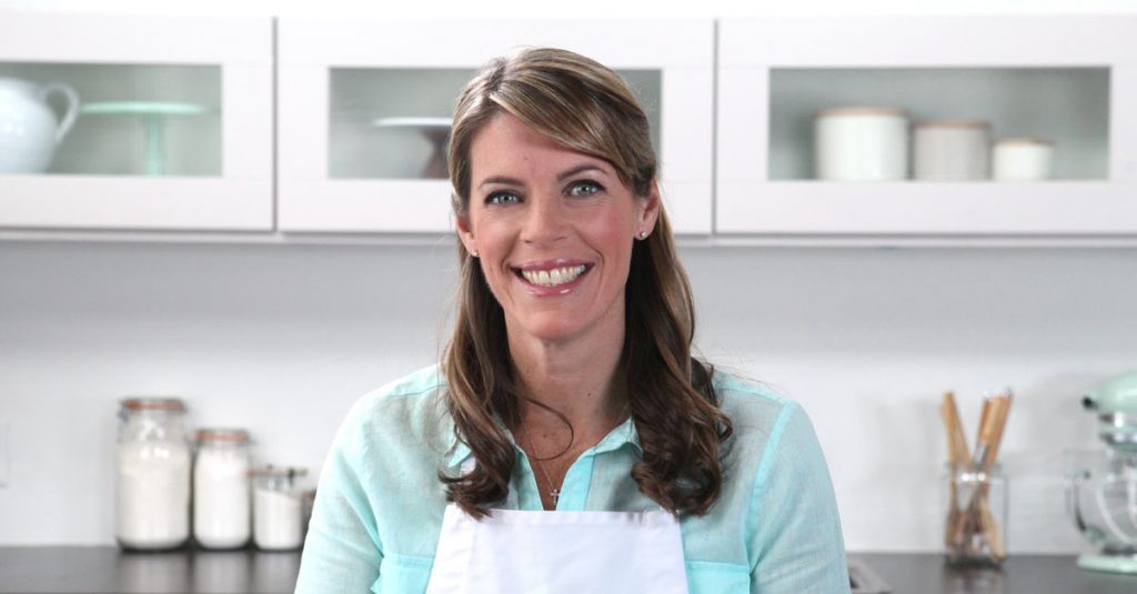 Woman in an apron smiling in a kitchen