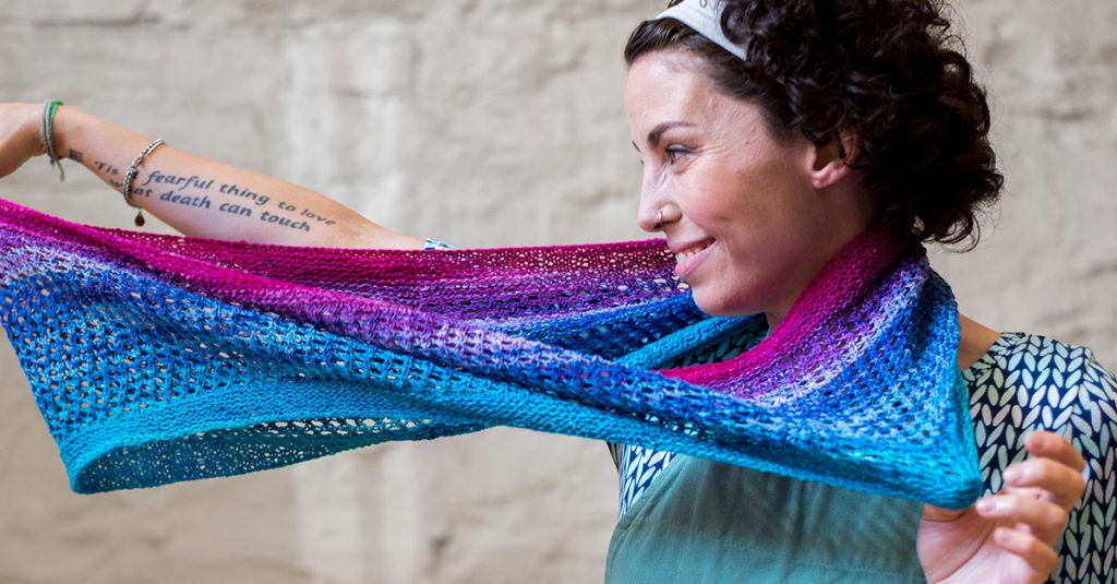 Woman holding a colorful blue pink and purple knit scarf