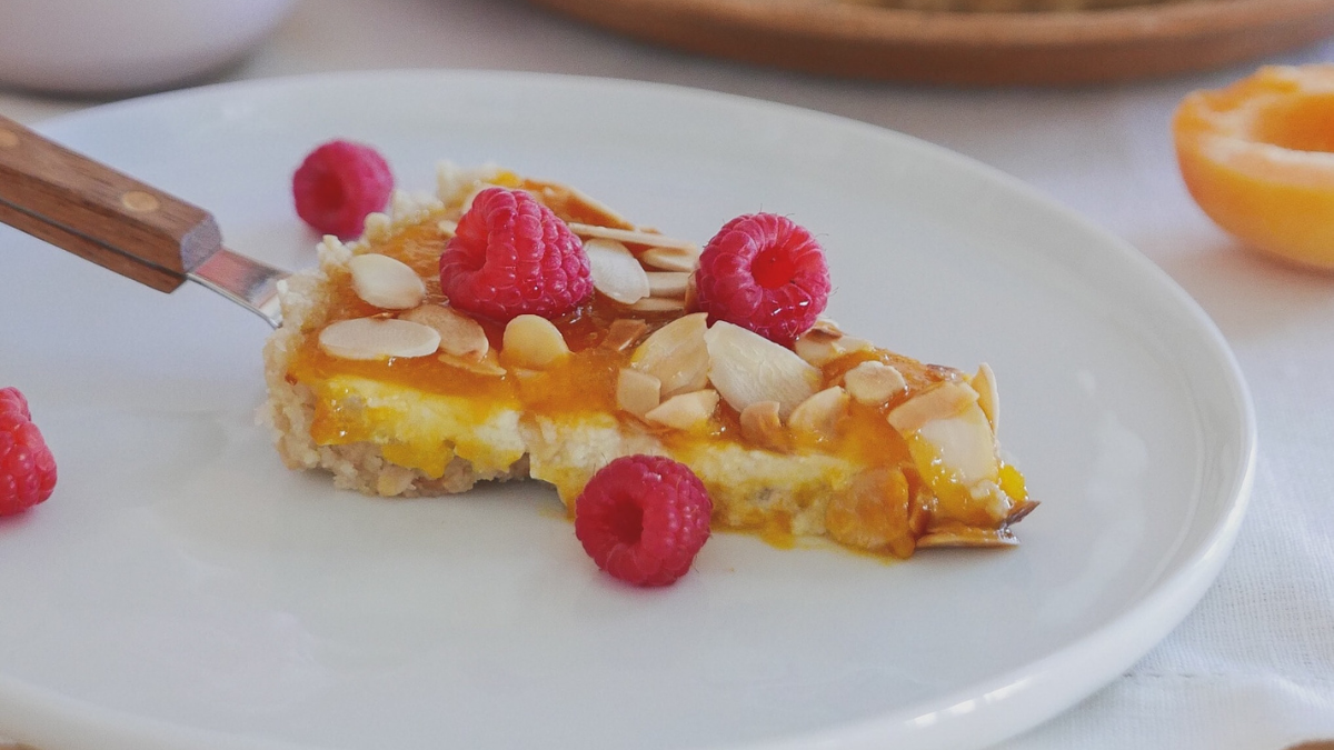 a white plate topped with a piece of cake and raspberries.