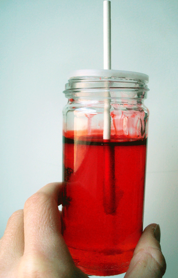 Inserting Lollipop Stick into Colorful Jar of Sugar