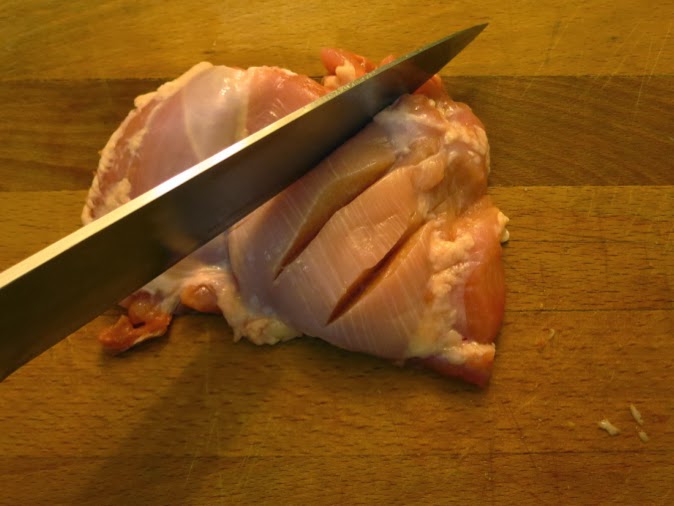 Cutting slashes in chicken to let the marinade soak in