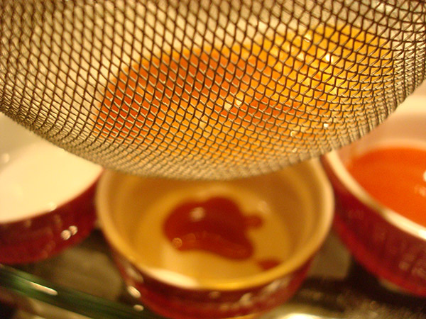 Straining Hardened Pieces of Carmel for Flan