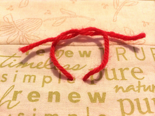 Square knot in red yarn on a quilt