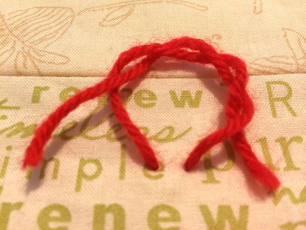 Surgeon's Knot in red yarn on a quilt
