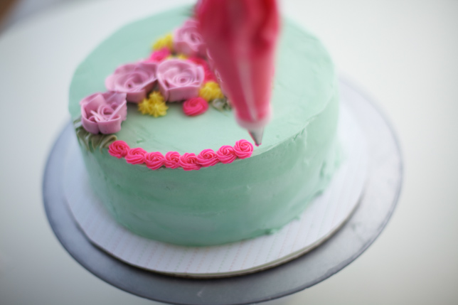 adding foliage to the bouquet cake with a piping bag