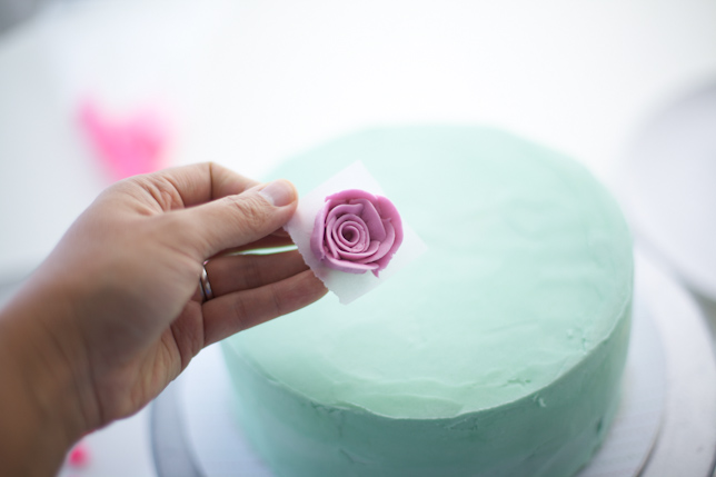 placing buttercream rose on layer cake