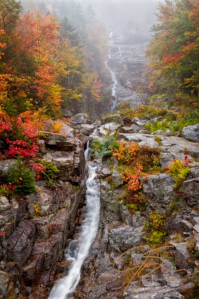 Silvery cascading waterfall through an autumn forest