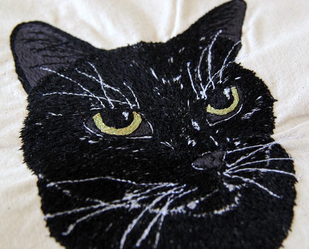 Free-hand machine embroidery of black cat on calico