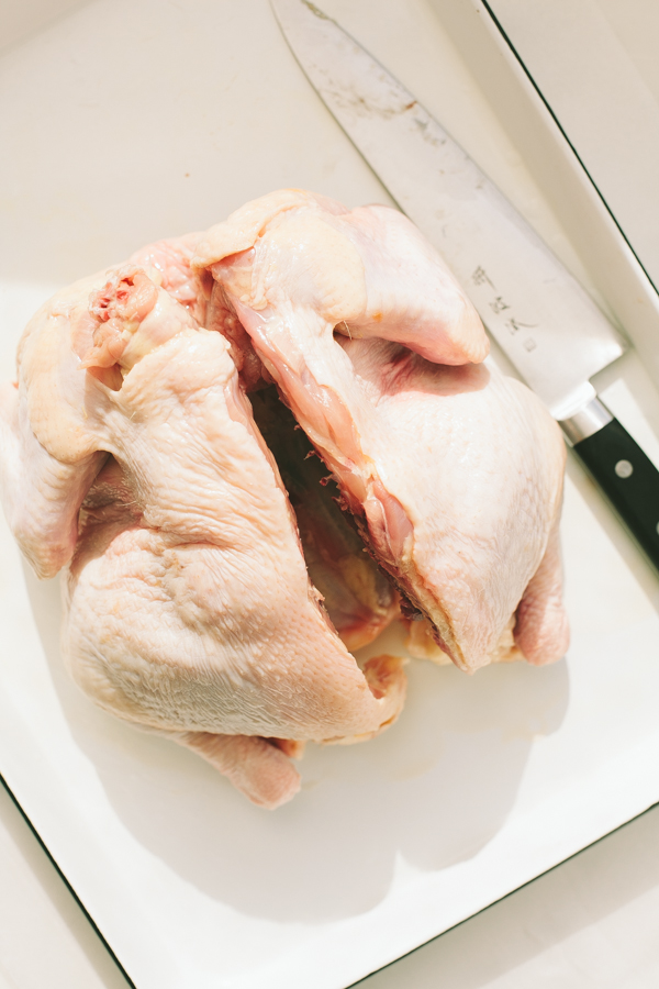 Slicing a fresh chicken in half for spatchcocking