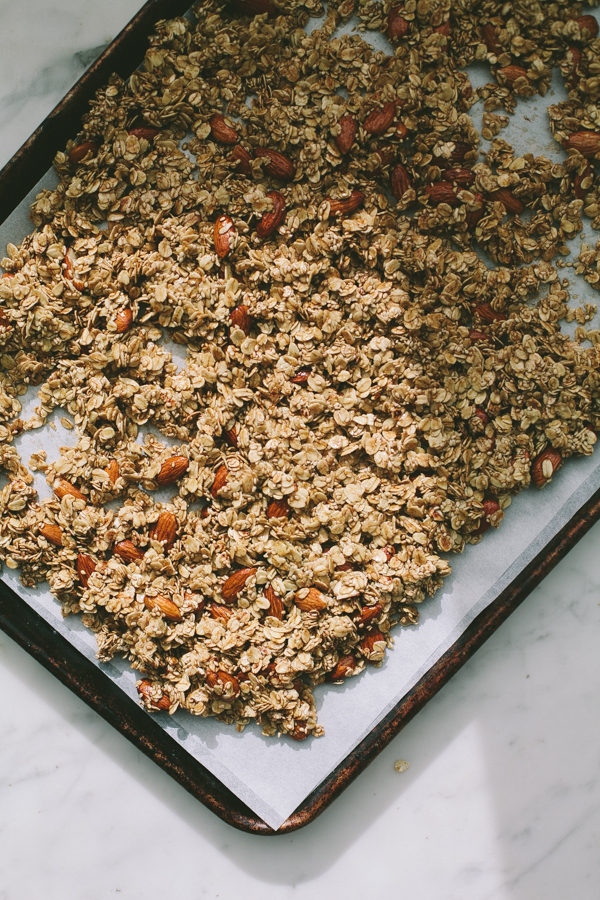 Spreading granola mixture evenly on a baking sheet