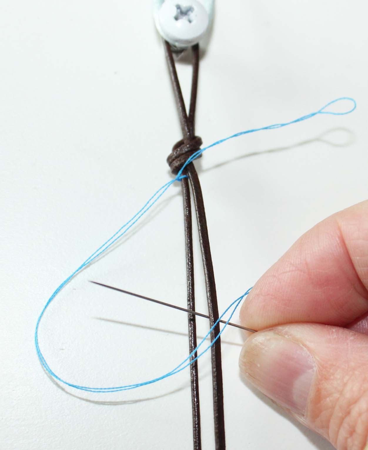 Add thread to leather. Tie on with knot .