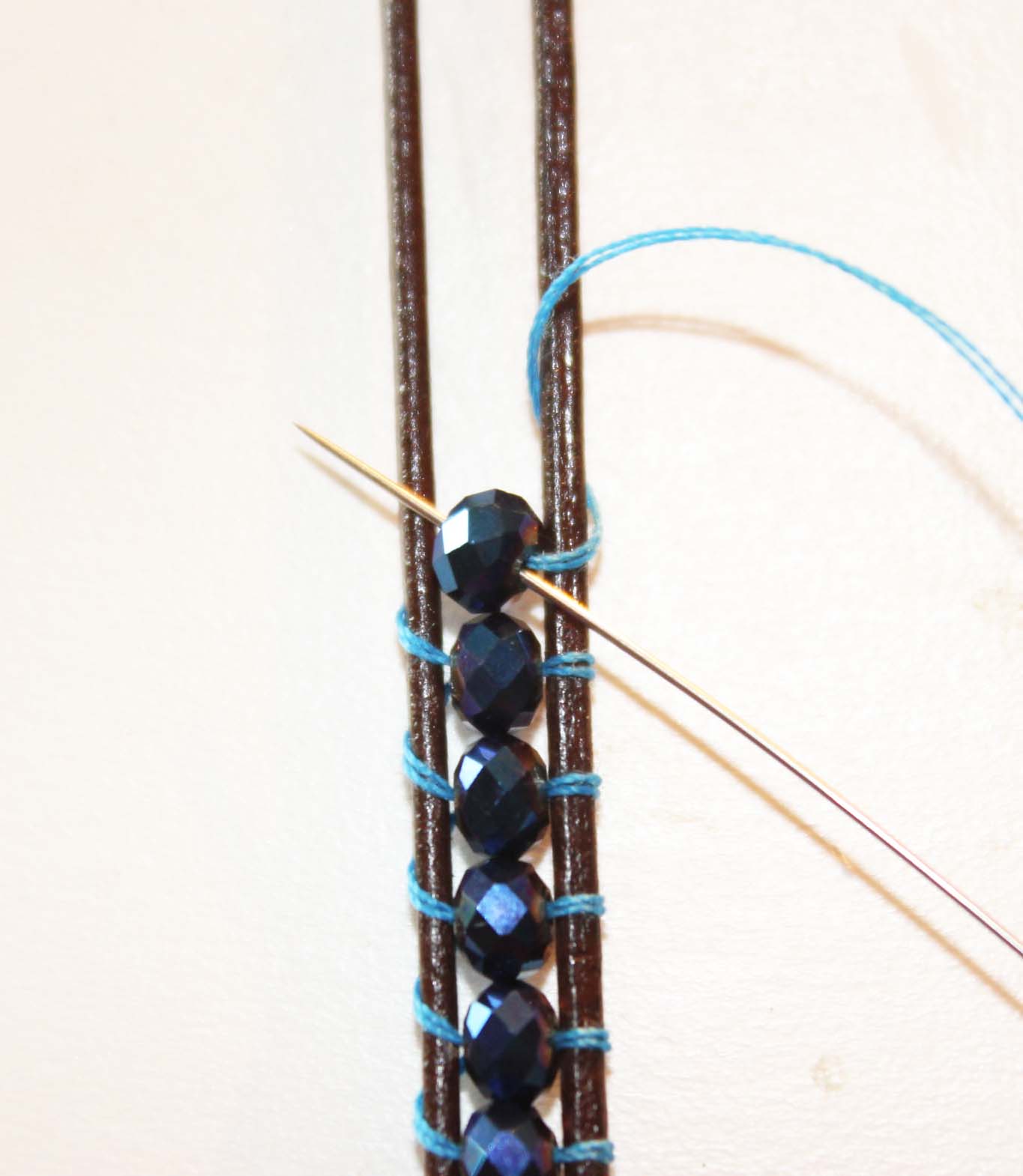 Back through the center of the bead and out over the top of the cord on opposite side