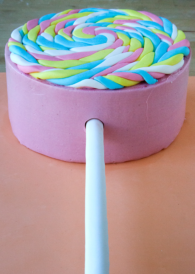 Inserting fondant lollipop stick into layer cake