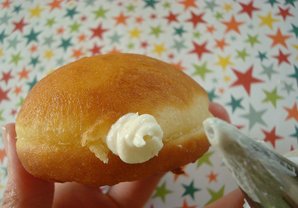 Filling homemade doughnut with traditional cream filling