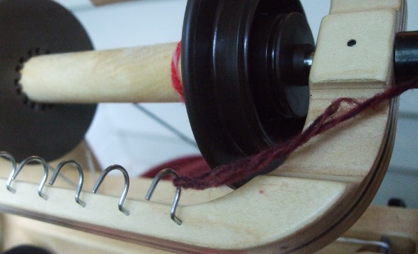 yarn tied to a hook of a spinning wheel flyer