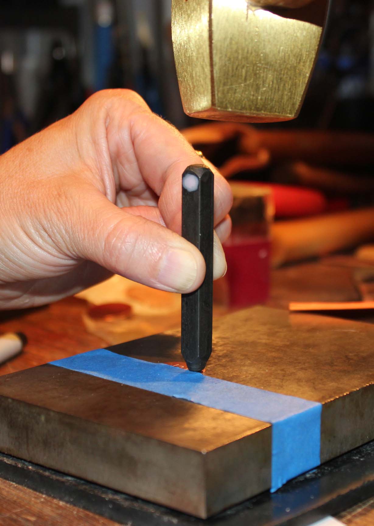 brass hammer striking the metal stamp