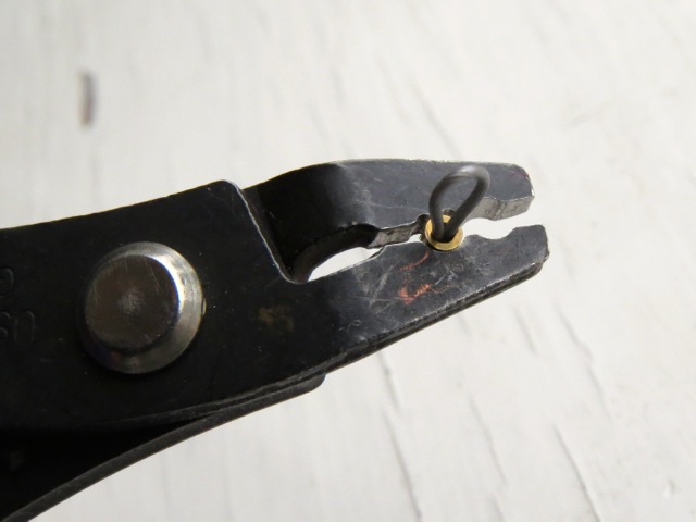 A crimp tube being held within crimping pliers