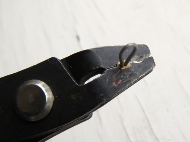 A crimp tube being squashed within crimping pliers