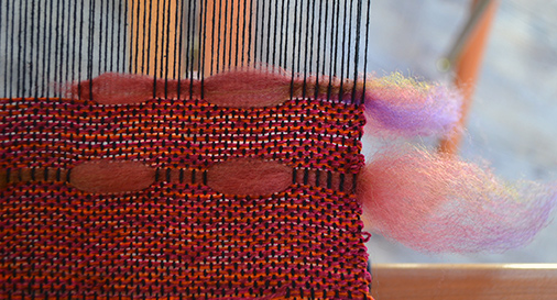 placement of wool sliver at the edge of a weaving in progress