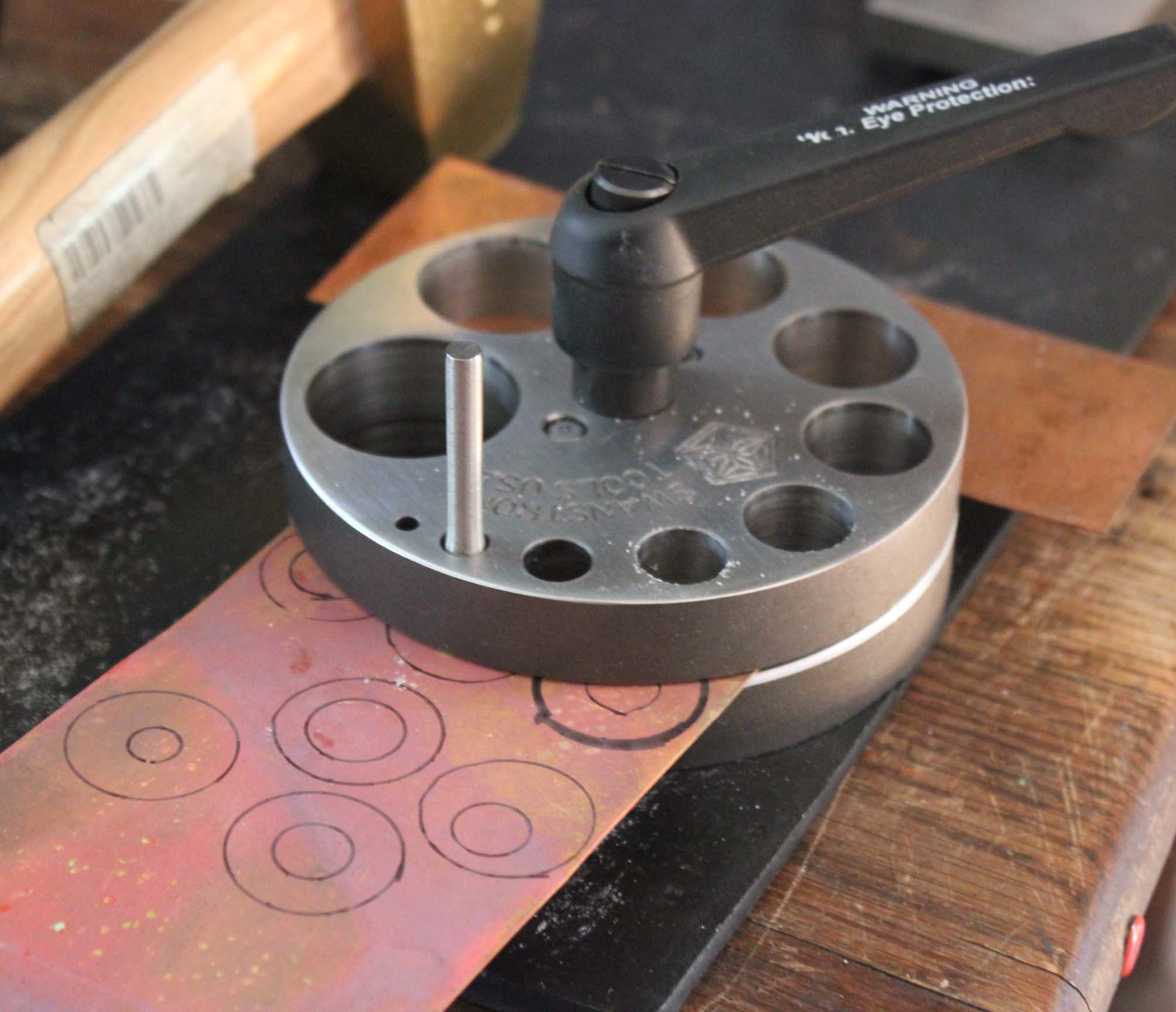 Insert copper sheet into disc cutter. Punch inner disc first.