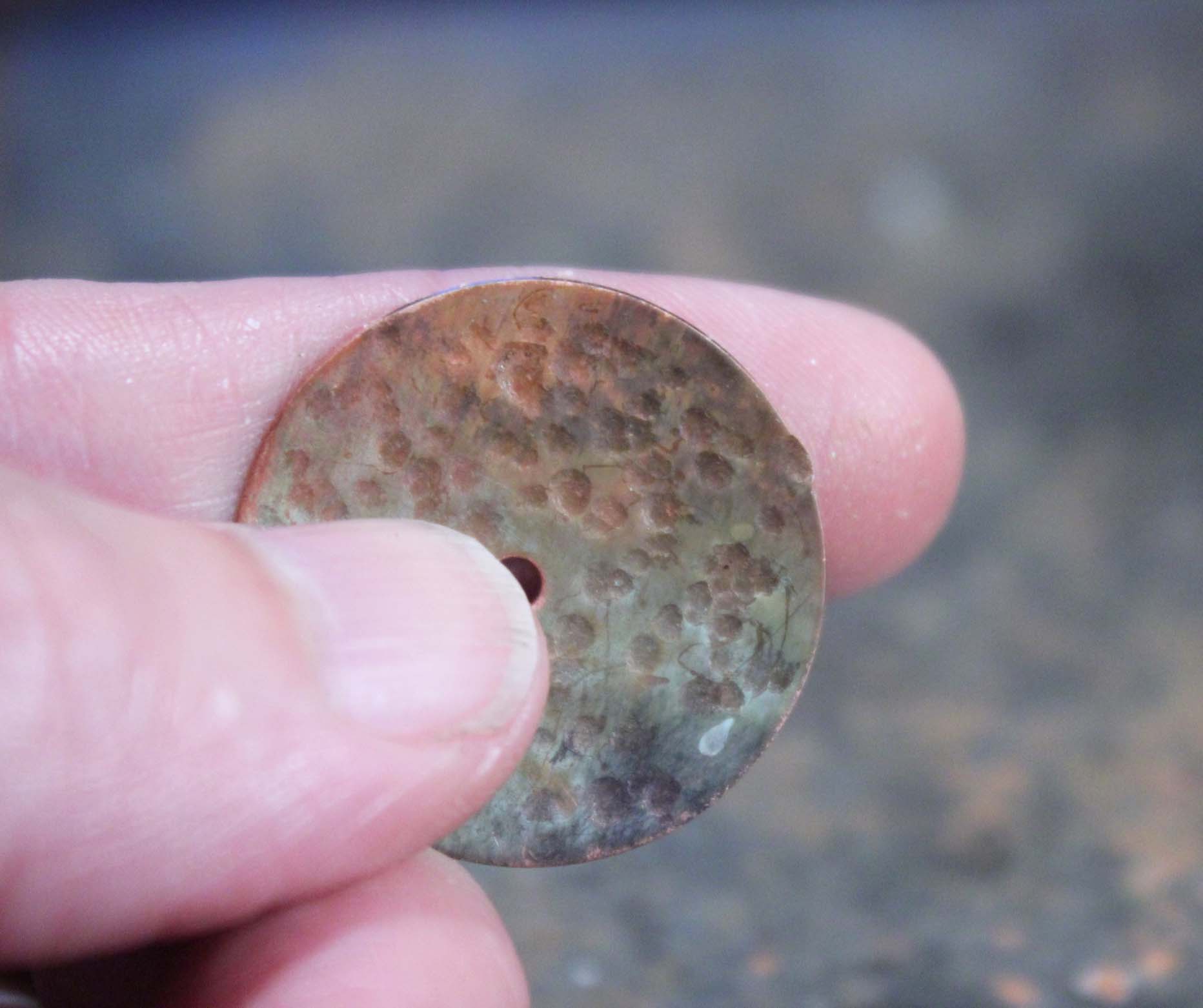 copper disc with uneven edge caused from striking with a ball peen hammer