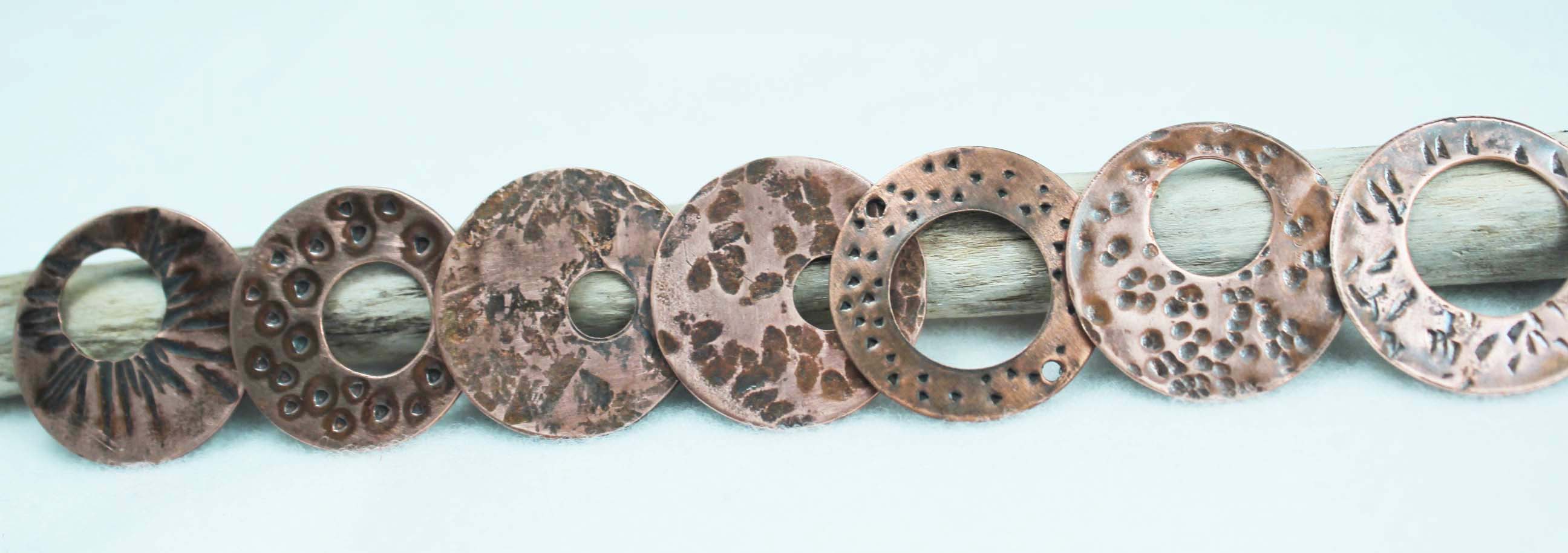 Seven copper discs sporting a variety of added textures