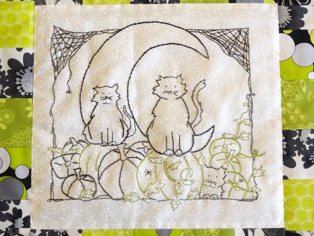 hand embroidery pattern of two black cats sitting on pumpkins surrounded by cobwebs