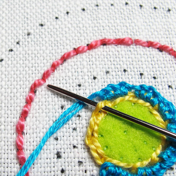 Working the buttonhole stitch over the outer loops of the chain stitch