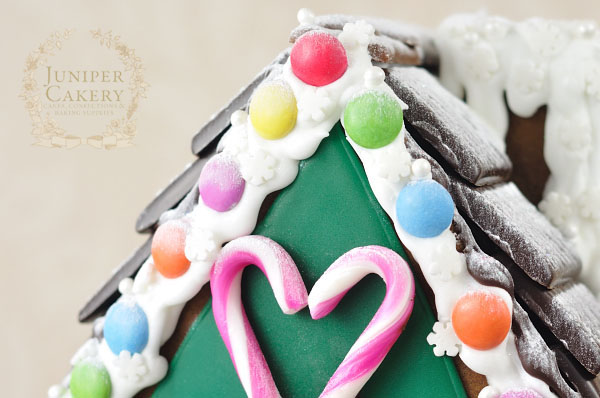 Decorating a festive gingerbread house with cookies, candies and sprinkles
