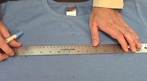 Marking embroidery design center on shirt.