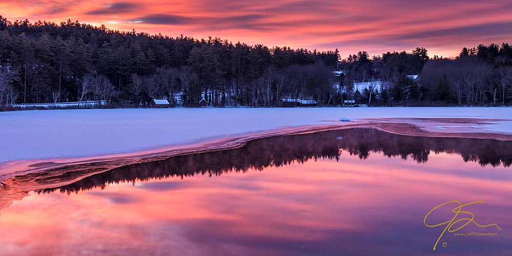 Warm fiery sunrise sky over partially frozen Little Lake, Tamworth, NH