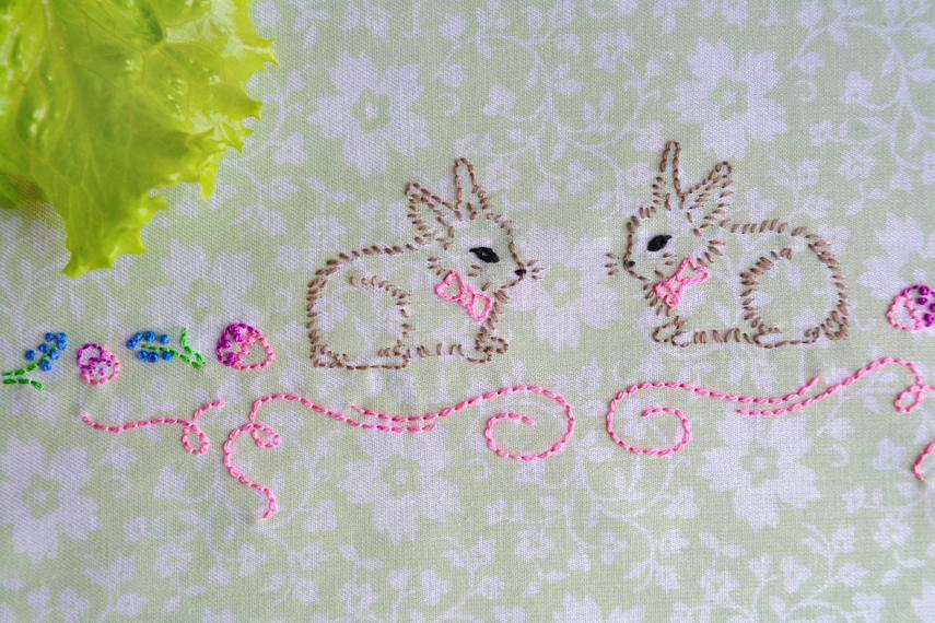 hand embroidered bunnies in brown on green floral cloth