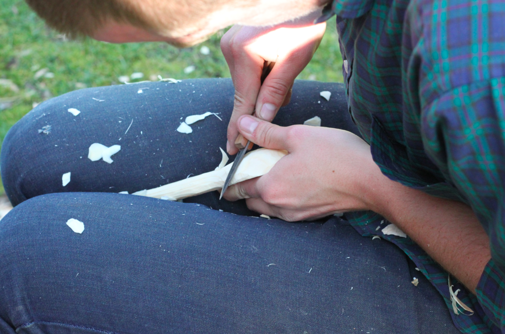 refining the handle of the spoon with a carving knife